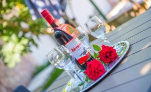 eine Flasche Wein und rote Rosen auf dem Tisch in der Unterkunft Villa Dalia in Mostar