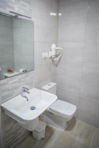 Baño blanco con aseo y lavamanos en Apartamentos pilucha, en Muxía