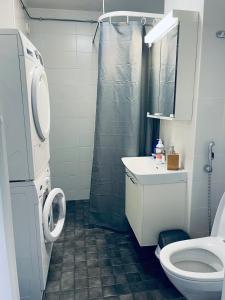 La salle de bains est pourvue de toilettes, d'un lavabo et d'une douche. dans l'établissement Kalastajankuja Apartment, à Espoo