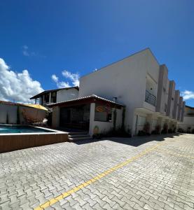 a large white building with a pool in front of it at Condomínio Lajú in Porto Seguro