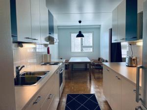 a kitchen with white cabinets and a dining table at Kalastajankuja Apartment in Espoo