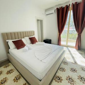 a bedroom with a large white bed in front of a window at Hotel Blue Eyes in Vlorë