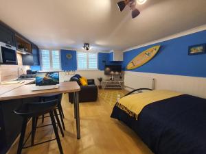 a bedroom with a bed and a kitchen with a surfboard on the wall at Hayling Hideaway, private cosy annex near to beach in South Hayling