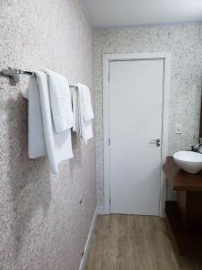 uma casa de banho com um lavatório e toalhas penduradas numa parede em Ipê Amarelo Cama e Café em Gramado