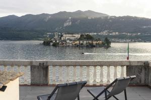 two chairs sitting on a balcony overlooking a body of water at Orta Paradise 4 in Orta San Giulio