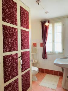 ein Bad mit einer roten Tür, einem WC und einem Waschbecken in der Unterkunft La Fabbrica Delle Idee B&B in Fonte