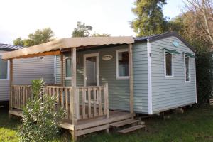 une petite maison avec une véranda et un auvent dans l'établissement Camping Lou Cabasson, à Bormes-les-Mimosas