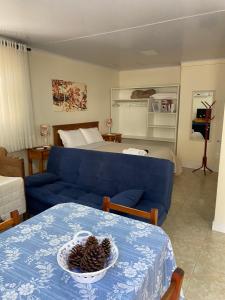 sala de estar con sofá azul y cama en Ipê Amarelo Cama e Café en Gramado