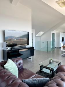 a living room with a couch and a large screen tv at Luxury Laurus Penthouse with awesome sea view in Primošten