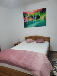 a bedroom with a bed with a painting on the wall at Colt de Rai in Berislăveşti