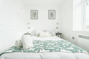 a white bedroom with a bed with a green and white blanket at The Royal Bell Apartments - Central Bromley in Bromley