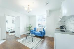 a living room with a blue couch and a table at The Royal Bell Apartments - Central Bromley in Bromley