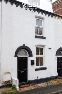 a white house with a black door and windows at 2 Bedroom Terrace Cottage, Parking, 5 minutes drive to Royal Shrewsbury Hospital in Shrewsbury