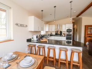 a kitchen with white cabinets and a table with stools at Gloccamaura in Newton Abbot