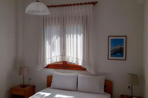 sypialnia z łóżkiem i oknem z białymi zasłonami w obiekcie Helen's house w mieście Pefkochori
