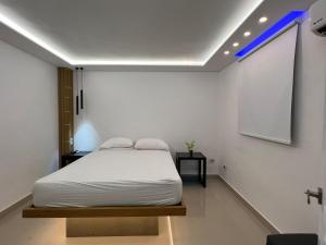 a bedroom with a white bed and a projection screen at Alegria Hostal in Santiago de los Caballeros