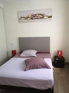 a bed with two pillows and a picture on the wall at COSY 2P A 5 MINUTES A PIED DE LA MER ET DU CENTRE in Menton