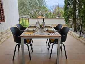 a wooden table with chairs and a bottle of wine at Jandom in Malinska