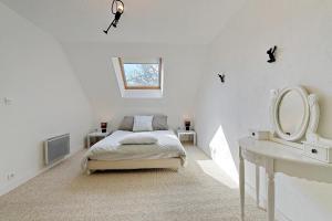 ein weißes Schlafzimmer mit einem Bett und einem Spiegel in der Unterkunft La Coquelière - Belle maison pour 5 in Putanges
