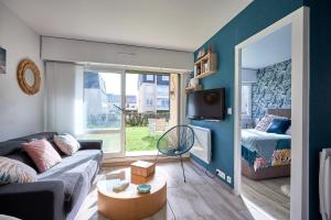 uma sala de estar com um sofá, uma televisão e uma cama em Overlord - Appt 300m plage em Courseulles-sur-Mer