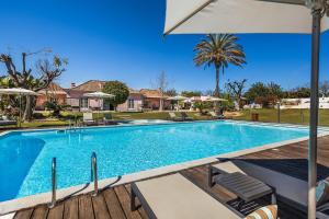 a swimming pool with an umbrella and chairs at Quinta de Santa Margarida - Charm Country House in Tavira