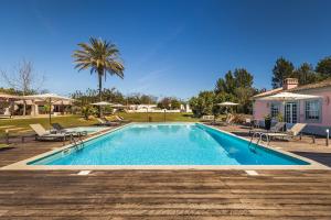 a swimming pool with chairs and a house at Quinta de Santa Margarida - Charm Country House in Tavira