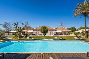 a swimming pool in front of a house at Quinta de Santa Margarida - Charm Country House in Tavira