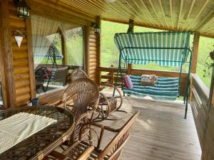 a porch with chairs and a hammock on a cabin at Ozgur Villa Home in Uğurlu