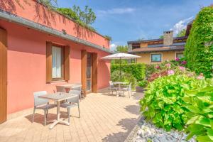 a patio with tables and chairs and an umbrella at B&B San Rocco in Capo di Ponte