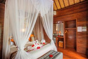 a bedroom with a canopy bed with white curtains at Tatak Bunut Private Villa in Nusa Lembongan