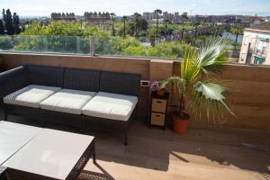 uma varanda com um sofá, uma mesa e uma planta em Puerta Palma con vistas únicas y aparcamiento em Badajoz