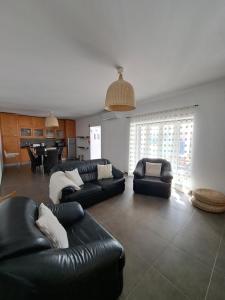 sala de estar con muebles de cuero negro y piano en Villa Caballero, en Alfundão