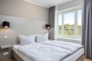 een slaapkamer met een wit bed en een raam bij Strandresidenzen Strandresidenzen Haus Dänholm 3 5 in Binz