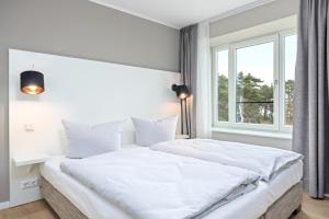 sypialnia z dużym białym łóżkiem i oknem w obiekcie Strandresidenzen Strandresidenzen Haus Dänholm 3 3 w mieście Binz