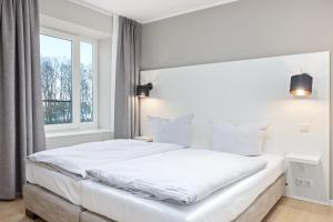 een slaapkamer met een groot wit bed en een raam bij Strandresidenzen Strandresidenzen Haus Dänholm 3 4 in Binz