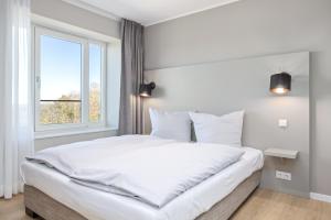 1 dormitorio con 1 cama blanca grande y ventana en Strandresidenzen Strandresidenzen Haus Dänholm, en Binz