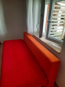 a red couch in a room with a window at Apartment Anić in Šmrika