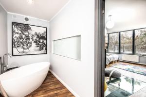 a bathroom with a white tub and a window at Bosque in Rogowo