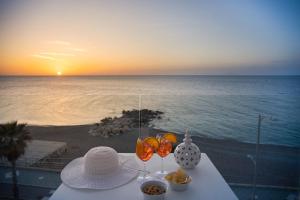 卡普多蘭多的住宿－Seaside Hotel，沙滩上一张桌子,上面放着玻璃杯和碗