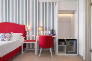 1 dormitorio con cama, silla roja y escritorio en Seaside Hotel, en Capo dʼOrlando