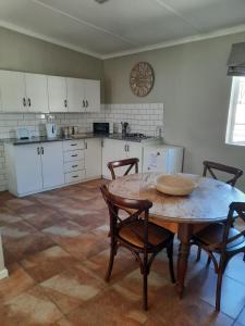eine Küche mit einem Tisch und Stühlen sowie einer Uhr an der Wand in der Unterkunft Little Milner Cottage in Queenstown