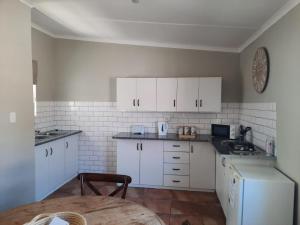 a kitchen with white cabinets and a table in it at Little Milner Cottage in Queenstown