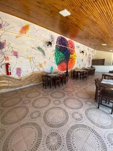 a restaurant with tables and a wall with a mural at Hotel Boituva Inn - Your Hotel in Boituva