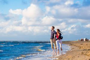Ein Mann und eine Frau, die am Strand spazieren in der Unterkunft Ferienpark Harmsen in Cuxhaven