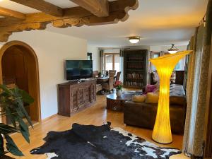 Alpen Suite Tegernsee - große Sonnenterasse und idyllischer Garten في باد ويسي: غرفة معيشة مع مزهرية صفراء كبيرة في الوسط