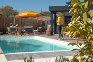 a woman standing next to a swimming pool with an orange tree at VILLA PIERARTLOU in Arès