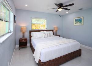 1 dormitorio con 1 cama blanca grande y ventilador de techo en Paradise Vacation Home, en Boynton Beach