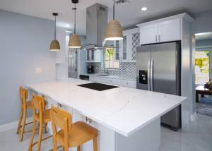 a kitchen with a white counter top and wooden chairs at Paradise Vacation Home in Boynton Beach