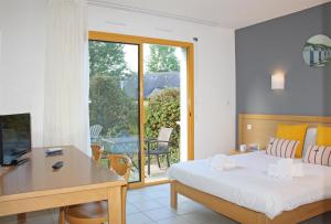 una camera d'albergo con letto, scrivania e finestra di Azureva Tregunc a Trégunc