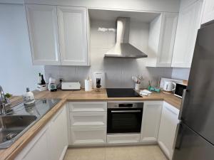 eine Küche mit weißen Schränken und einer Spüle und einem Herd in der Unterkunft EDIFICIO CORUÑA CALA DE FINESTRAT. Luxury apt. in Benidorm